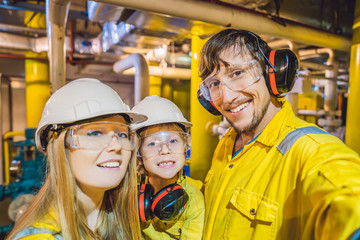 Mom, Dad and Son in a yellow work uniform, glasses, and helmet in an industrial environment, oil Platform or liquefied gas plant