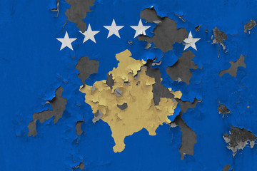 Close up grungy, damaged and weathered Kosovo flag on wall peeling off paint to see inside surface.