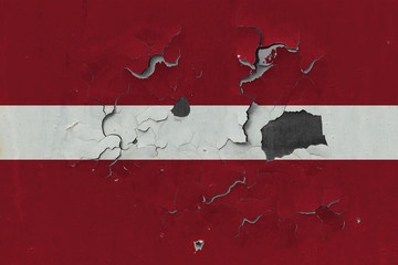 Close up grungy, damaged and weathered Latvia flag on wall peeling off paint to see inside surface.