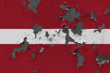 Close up grungy, damaged and weathered Latvia flag on wall peeling off paint to see inside surface.