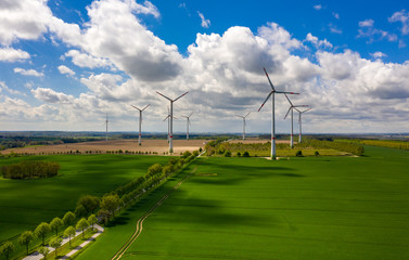 Fototapeta na wymiar wind turbines in green field - clouds in the sky