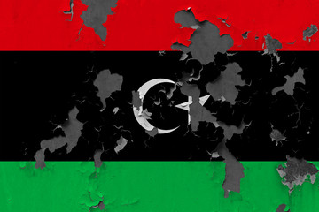 Close up grungy, damaged and weathered Libya flag on wall peeling off paint to see inside surface.