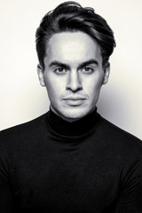 Male beauty concept. Portrait of handsome young man with stylish haircut posing over gray background. Perfect hair & skin. Close up. Studio shot