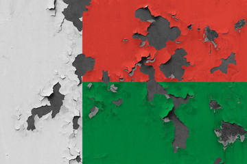 Close up grungy, damaged and weathered Madagascar flag on wall peeling off paint to see inside surface.