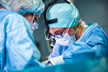Surgeon and his assistant performing cosmetic surgery on nose in hospital operating room. Nose...