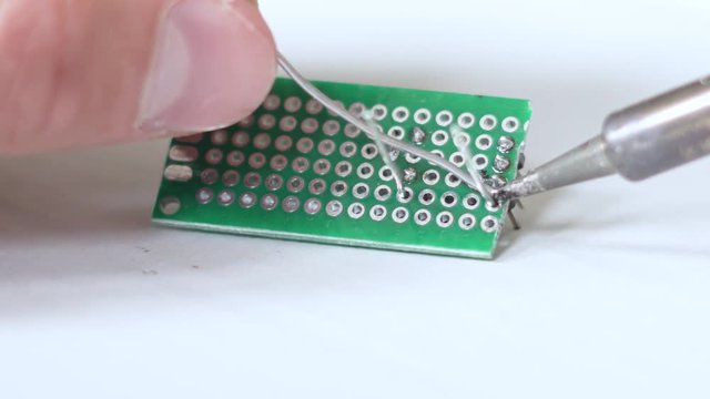 Close up of male person soldering a self made circuit. Veroboard self cut. Amateur.