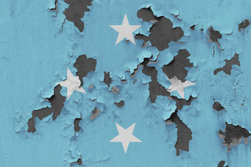 Close up grungy, damaged and weathered Micronesia flag on wall peeling off paint to see inside surface.