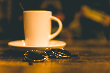 cup of coffee in a wooden pub with round sunglasses