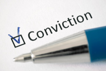 Questionnaire. Blue pen and the inscription CONVICTION with check mark on the white paper