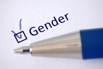 Questionnaire. Blue pen and the inscription GENDER with check mark on the white paper