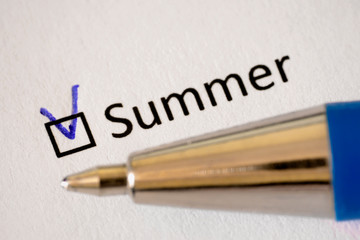 Fototapeta premium Questionnaire. Blue pen and the inscription SUMMER with check mark on the white paper