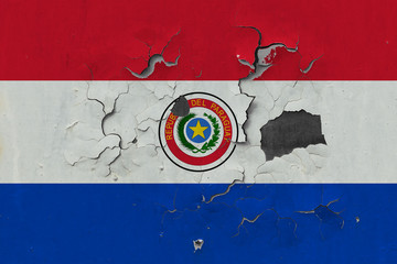 Close up grungy, damaged and weathered Paraguay flag on wall peeling off paint to see inside surface.