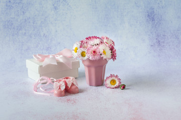 Its a girl, pink theme Baby Shower. Newborn accessories for a baby girl on a pastel background with daisies. Soft focus, place for text, close up.
