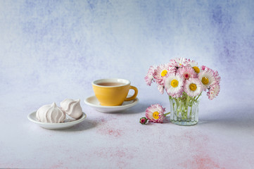 Obraz na płótnie Canvas Cup of tea with white meringues and daisies in vase. Morning surprise. Minimalism, soft focus, place for text, close up.