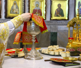 Orthodox Church. The priest covers the silver cup for communion, prospor on the throne.