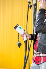Happy woman charging electric car on charging station
