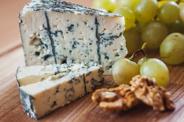 closeup dorblu cheese slice with wallnuts and green grape