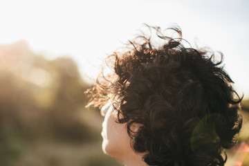 Back portrait of young woman walking in a meadow at sunset. Beautiful woman portrait at dawn in the countryside.