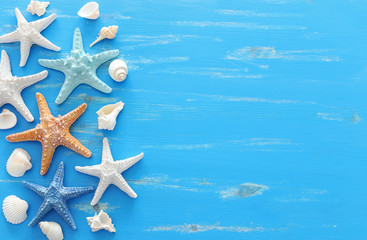 Fototapeta na wymiar vacation and summer concept with starfish and seashells over blue wooden background. Top view flat lay
