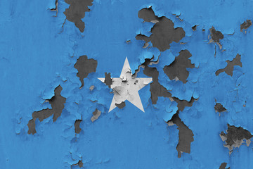 Close up grungy, damaged and weathered Somalia flag on wall peeling off paint to see inside surface.