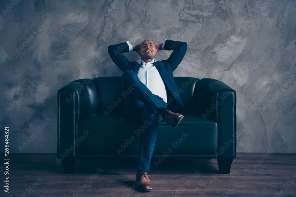 Wall mural Nice stylish trendy classy attractive cheerful guy professional top ceo boss chief banker financier sitting on couch having rest at work place station gray concrete wall