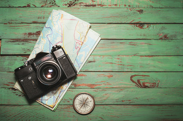 Old vintage photo camera with map and compass  on wooden background
