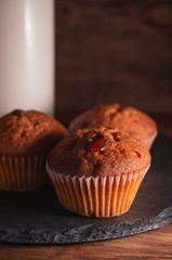 Fresh juicy muffins and a glass of milk on rustic wooden background