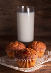 Fresh juicy muffins and a glass of milk on rustic wooden background