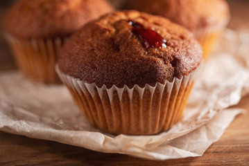 Fresh juicy muffins on rustic wooden background