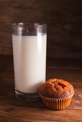 Fresh juicy muffins and a glass of milk on rustic wooden background