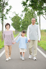手をつなぎ微笑む祖父母と孫