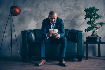 Portrait of nice classy elegant attractive busy guy wearing jacket suit top manager sitting on couch account budget balance at workplace station gray concrete wall