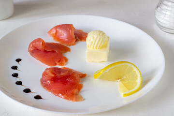 Trout, butter and lemon on a plate. White background