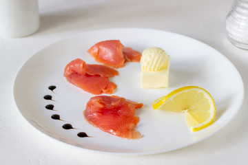 Trout, butter and lemon on a plate. White background
