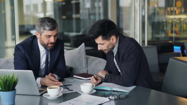 Business partners are discussing informating in charts arguing then tearing papers throwing expressing anger and disagreement. Meeting and talks concept.
