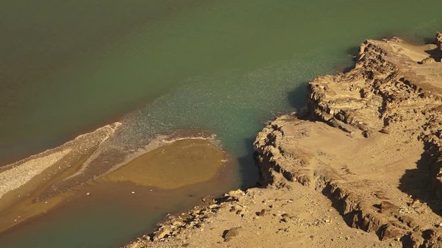 Extreme close up, high angle still shot of a shallow stagnant  green glacier  water or Indus river,  Its channel is filled with silt and sand.