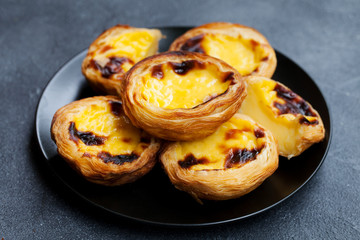Egg tart, traditional Portuguese dessert, pastel de nata on a plate. Grey stone background.