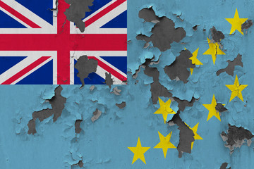 Close up grungy, damaged and weathered Tuvalu flag on wall peeling off paint to see inside surface.