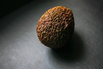 Whole avocado on black background top view