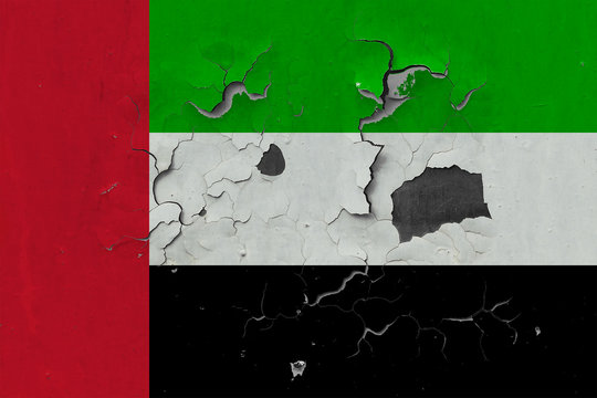 Close up grungy, damaged and weathered United Arab Emirates flag on wall peeling off paint to see inside surface.