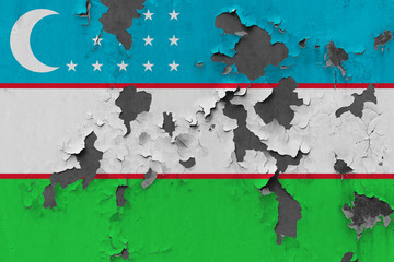 Close up grungy, damaged and weathered Uzbekistan flag on wall peeling off paint to see inside surface.