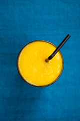 Fresh tropical fruit smoothie mango juice on blue background. Copy space. Top view.