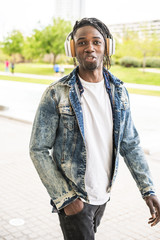 African American Guy smiling casual dress and with music headphones street.