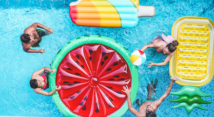 Happy friends playing with air lilo ball inside swimming pool - Young people having fun on summer holidays vacation - Travel, holidays, youth lifestyle, friendship and tropical concept