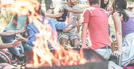 Fototapeta na wymiar Group of friends making picnic with barbecue on city park outdoor - Young people eating bbq meal and drinking wine at dinner in backyard - Focus on behind right guys - Youth and summer concept