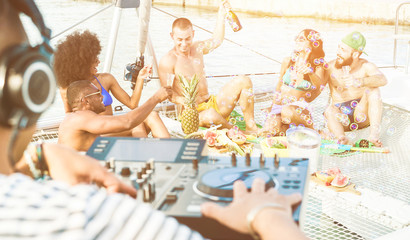 Happy friends drinking champagne in summer boat party - Young people having fun together with dj...