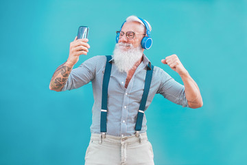 Senior hipster man using smartphone app for creating playlist music - Trendy tattoo guy having fun with mobile phone technology - Tech and joyful elderly lifestyle concept - Focus on his face