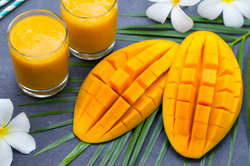 Fresh tropical fruit smoothie mango juice and fresh mango on grey background.