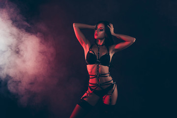 Portrait of nice cool gorgeous winsome attractive sportive perfect thin fit form shape line wavy-haired lady wearing swordbelt teasing posing isolated on black red light background