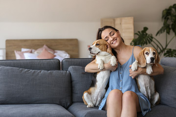 Young woman with cute dogs sitting on sofa at home